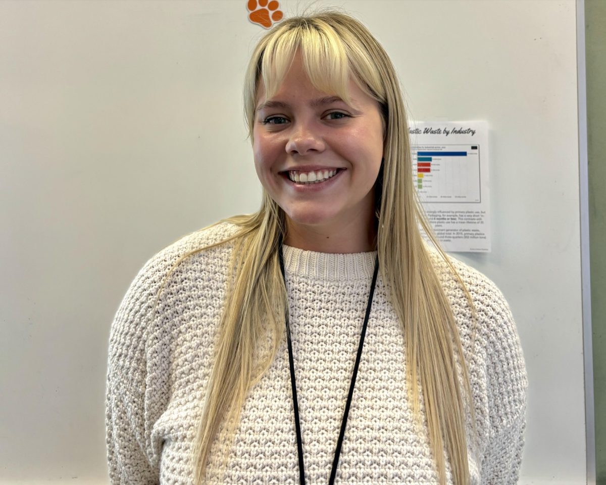 Mrs. Kyllo smiles in front of her classroom whiteboard. Friendly and open, she's always willing and eager to engage with students. 